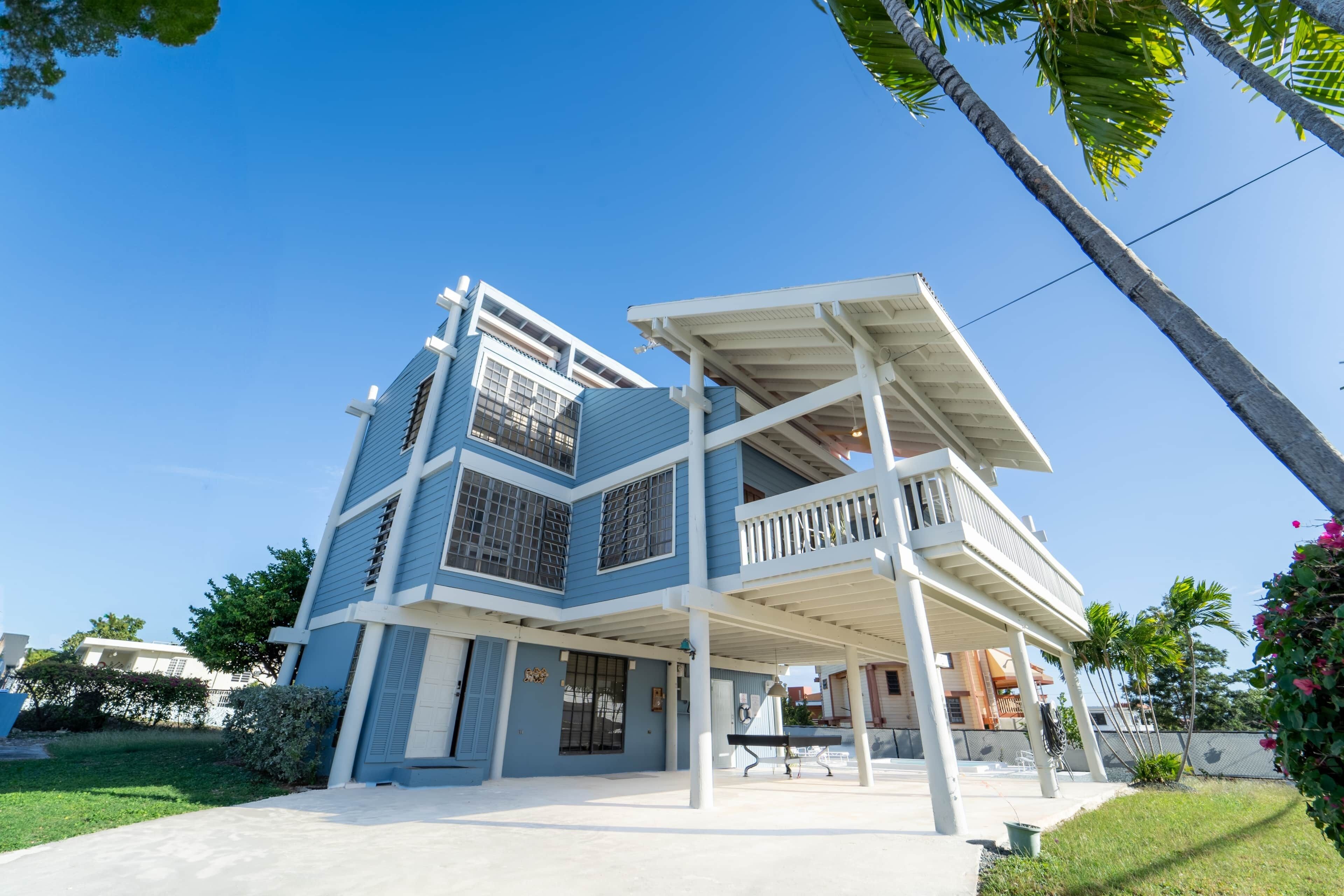A modern two-story building with a balcony, a covered patio, and a well-maintained lawn.