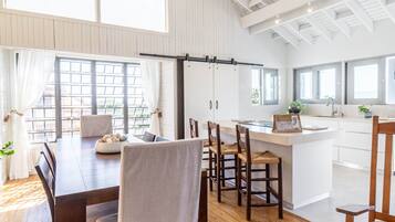 A spacious kitchen with a large island, wooden flooring, and a high ceiling with exposed beams.