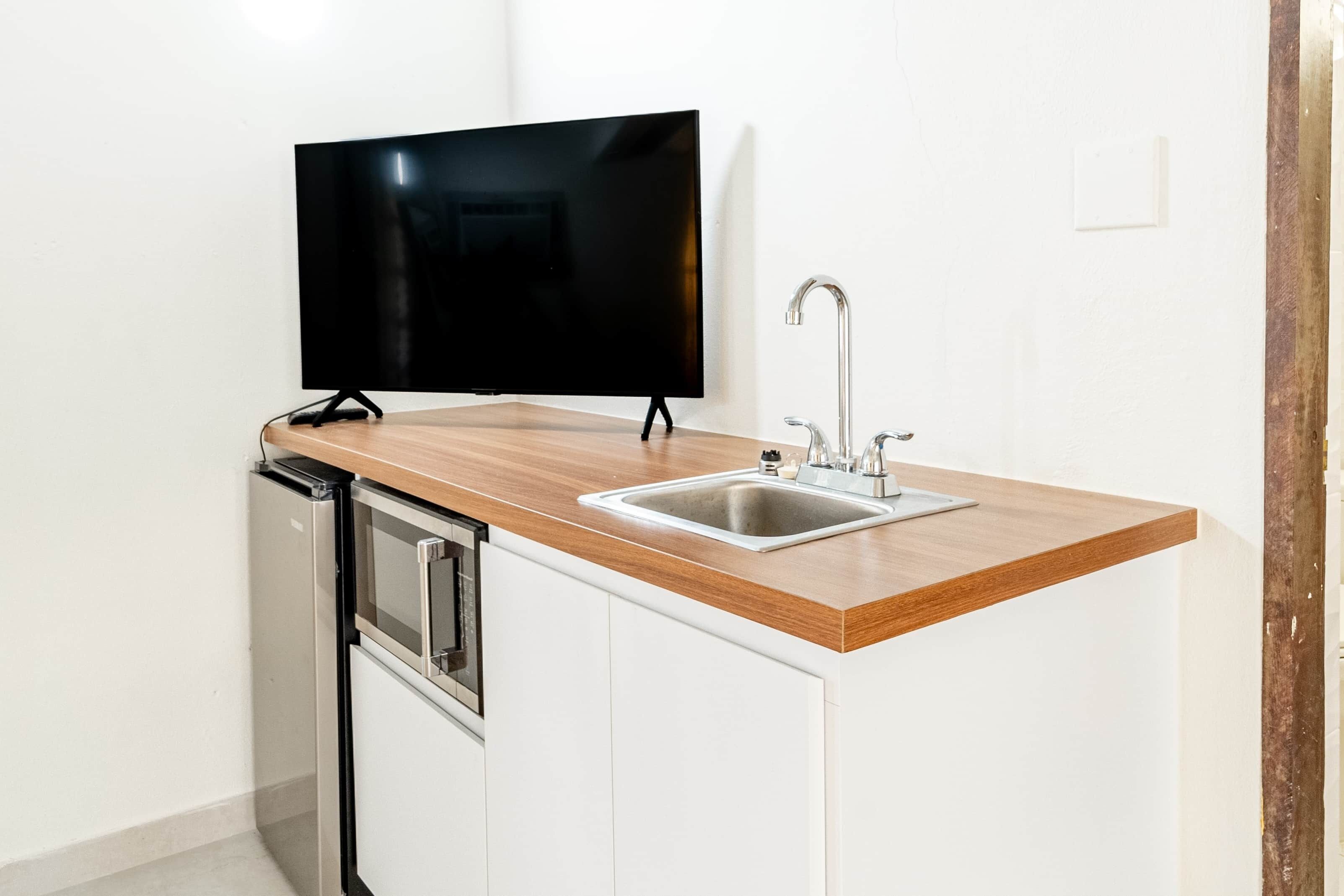 A kitchen with a flat-screen TV, a sink, and a dishwasher.