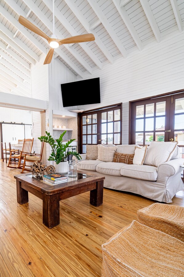 A spacious living room with a wooden coffee table, a white sofa, and a ceiling fan.