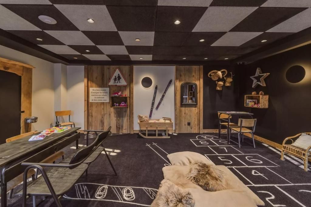 Una habitación con techo a cuadros, un banco de madera, una mesa con revistas y un sofá con una manta de piel.
