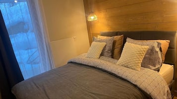A bedroom with a bed, a headboard, and a window with curtains.