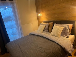 A bedroom with a bed, a headboard, and a window with curtains. - L'eclat D Veriaz Piscine Jacuzzi Megève (Megève)
