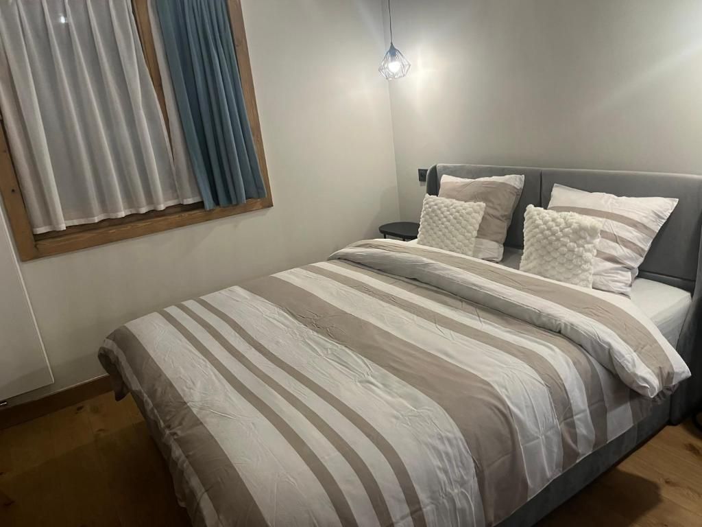 Ein Schlafzimmer mit einem Bett, Kissen, einem Nachttisch und einem Fenster mit Vorhängen.