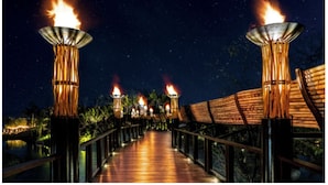 A wooden pathway with torches on either side, leading to a covered area with a view of the night sky. - One Bedroom Suite Grand Mayan, Vidanta's Luxury Beach Resort, VIP Theme Park acc (Nuevo Vallarta)