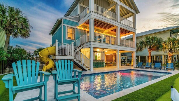 Une maison à deux étages avec une piscine, un espace salon extérieur et un toboggan.