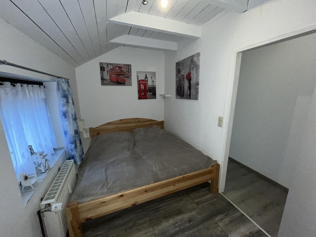 Un dormitorio con cama de madera, un radiador y una ventana con cortinas.