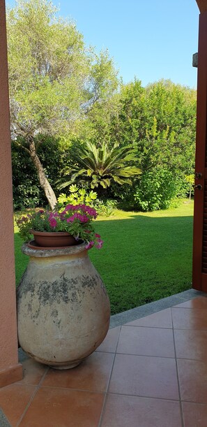 A large, weathered ceramic pot with pink flowers on a tiled patio. - House very close to Cinta Beach with a large lawn. (San Teodoro)