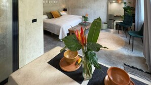 A modern hotel room with a large bed, a dining area, and a kitchen. - The Hidden Garden (San Marcos La Laguna)
