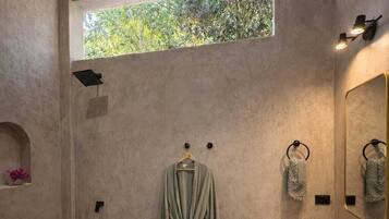 A modern bathroom with a large window, a freestanding bathtub, a sink with a mirror, and a robe hanging on a hook.