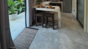 A modern kitchen with a central island, a hanging light fixture, and a view of greenery outside. - The Hidden Garden (San Marcos La Laguna)