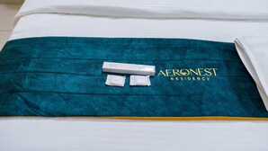 Ein Bett mit einer türkisfarbenen Decke und einem weißen Kissen, sowie eine weiße Box mit dem Text "AERONEST RESIDENCY".