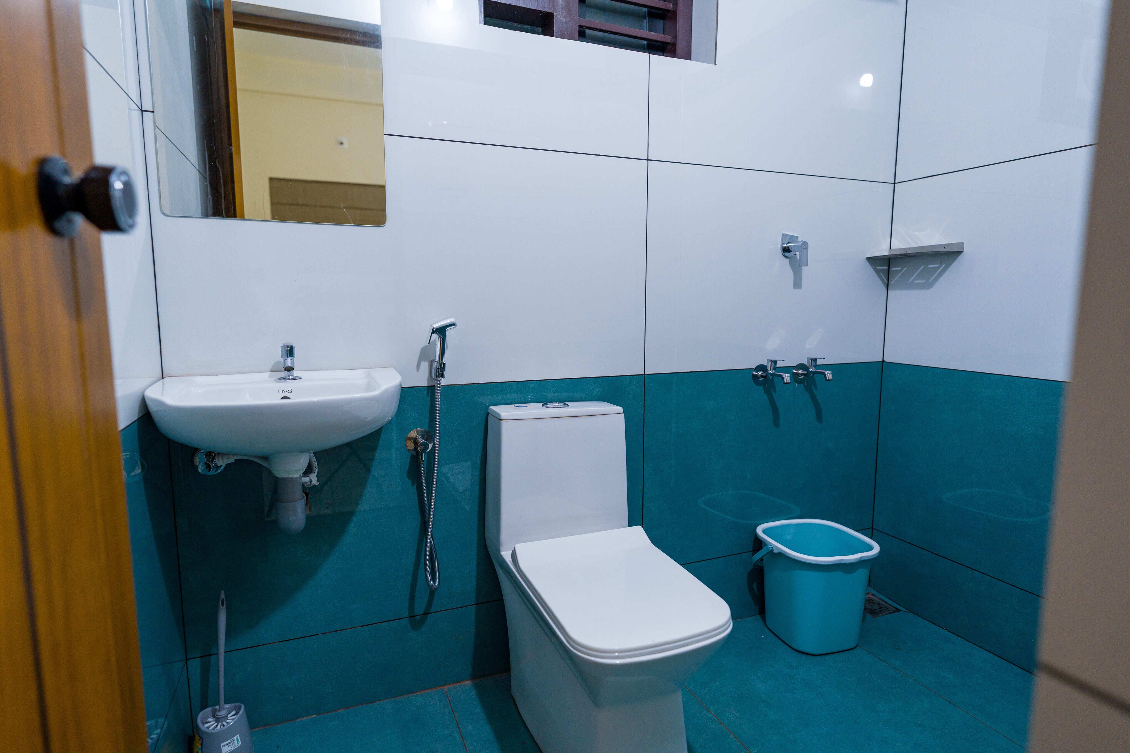 A bathroom with a white sink, toilet, and blue-tiled walls.