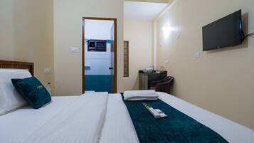 Una habitación de hotel con una cama, un televisor montado en la pared y un escritorio con una silla.