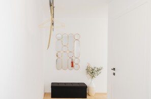 A minimalist room with a black bench, a wall-mounted mirror, and a small plant. - ANIMEA SUITES & APARTMENTS OSSIACHER SEE LAKE VIEW APARTMENTS (Annenheim)