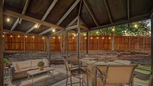 Ein Außenbereich mit Terrasse, überdachter Sitzgelegenheit, Holzdeck und rustikaler Holzumzäunung.