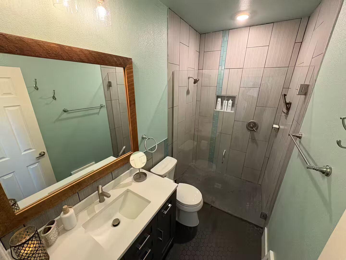 Een moderne badkamer met een grote spiegel, een wastafel, een toilet en een douche.