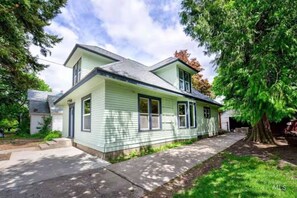 A two-story house with a front porch, a driveway, and a large tree in the yard. - Historic Craftsman Home (Moscow)