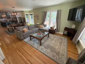 A spacious living room with a large sofa, a glass coffee table, and a wooden floor. - Historic Craftsman Home (Moscow)