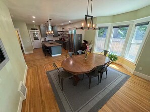 A spacious kitchen with a central island, a dining area with a wooden table and chairs, and large windows providing natural light. - Historic Craftsman Home (Moscow)