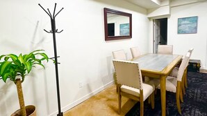 Ein Konferenzraum mit langem Tisch, Stühlen, einem Garderobenhaken, einem Blumentopf und einem gemusterten Teppich.