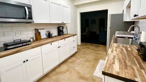 Eine moderne Küche mit weißen Schränken, einer Mikrowelle und Holz Arbeitsplatten.