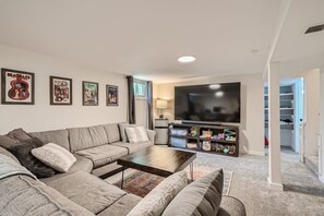 A living room with a sectional sofa, a coffee table, a flat-screen TV, and a bookshelf. - Modern Badass Bungalow (Lafayette)