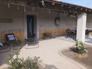 Eine Terrasseneinrichtung mit Sitzgelegenheiten, einem Schubkarren und einem kleinen Garten.