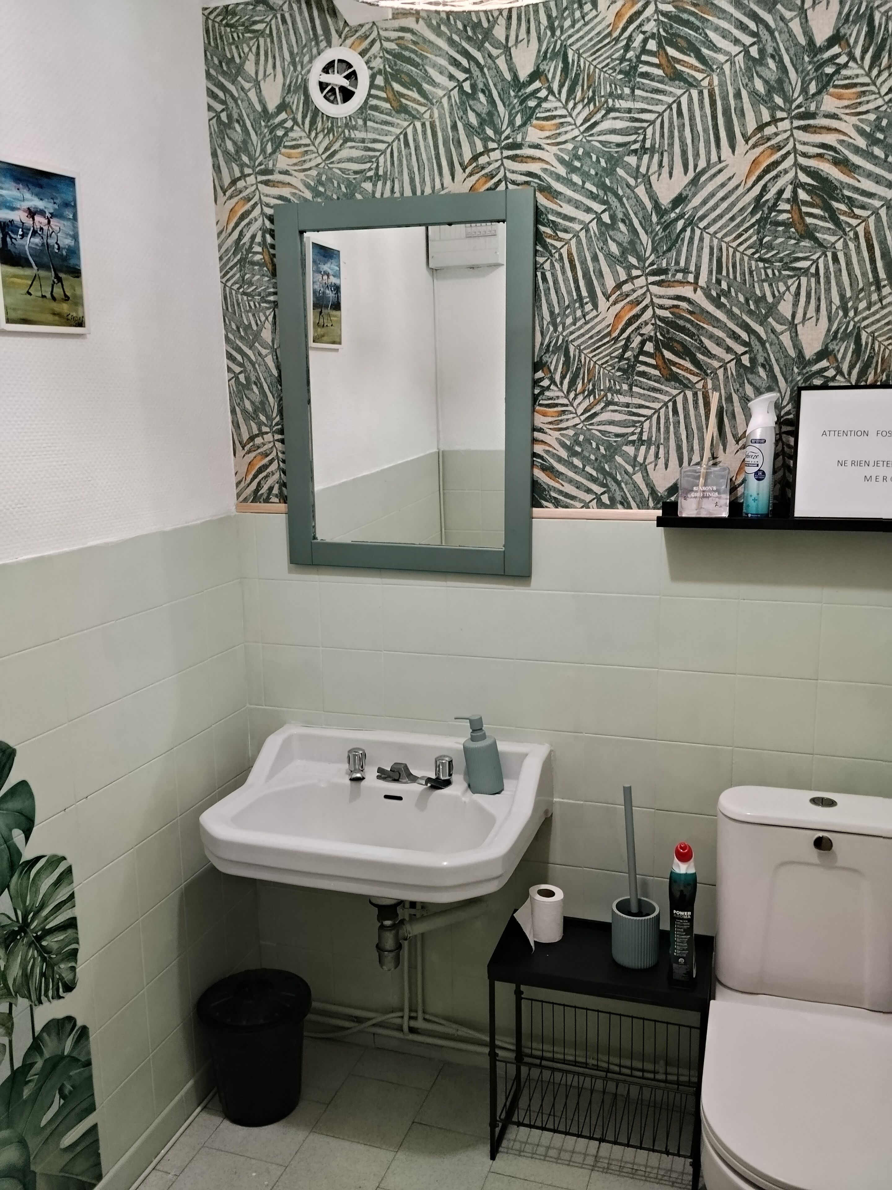 Un baño con lavamanos blanco, un espejo, un inodoro y un estante con artículos de tocador.