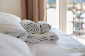 A neatly made bed with rolled towels and a view of a dining area through a window. - Suite Adige with Private Terrace, Wi-Fi and Air Conditioning (Verona)