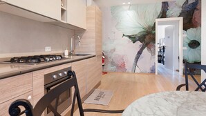 A modern kitchen with a gas stove, oven, and wooden cabinets. - Giulietta Suite with Private Bathroom, Balcony, Wi-Fi, and Air Conditioning (Verona)