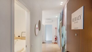 Un couloir avec un lit, un miroir et une pancarte indiquant « CHAMBRES REBALY ».
