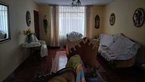 Una sala de estar con un sofá, una silla, una mesa con un florero y una planta en maceta.