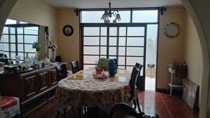 Un comedor con una mesa grande, sillas, una araña y vistas a través de una ventana.