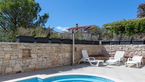 A swimming pool with steps, white lounge chairs, and a stone wall. - Apartman R&G Serenity (Ližnjan)