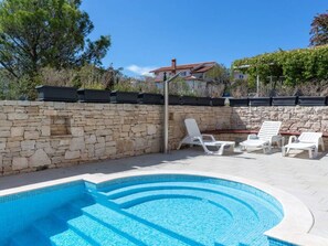 A swimming pool with steps, white lounge chairs, and a stone wall. - Apartman R&G Serenity (Ližnjan)