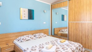 A bedroom with a bed, a nightstand, a mirror, and a wardrobe. - Apartman R&G Serenity (Ližnjan)