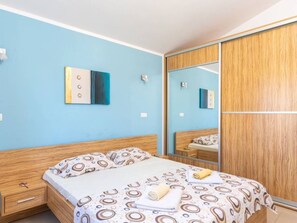 A bedroom with a bed, a nightstand, a mirror, and a wardrobe. - Apartman R&G Serenity (Ližnjan)