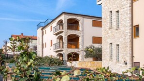 A multi-story building with stone facades, balconies, and a staircase leading to the entrance. - Apartman R&G Serenity (Ližnjan)