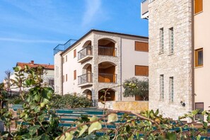 A multi-story building with stone facades, balconies, and a staircase leading to the entrance. - Apartman R&G Serenity (Ližnjan)