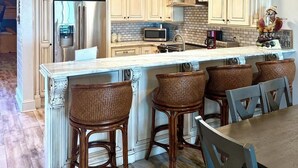 A kitchen with a central island, wooden chairs, and hanging pendant lights. - Gulfs Edge Townhome #16 - Sealee (Panama City Beach)