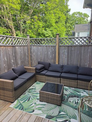 A wooden deck with a sectional sofa and a coffee table.