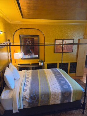 Habitación de hotel con cama, mesita de noche, espejo, un cuadro en la pared y armario.
