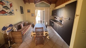 Un coin repas accueillant avec une table, des chaises, un ventilateur et un canapé.