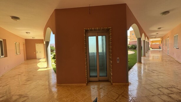 Un couloir avec une porte en verre donnant sur un balcon, un sol carrelé et un motif décoratif en forme d’étoile.
