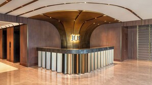 A reception area with a curved counter, a modern light fixture, and a wooden panel wall. - TUI BLUE Han River (Da Nang)