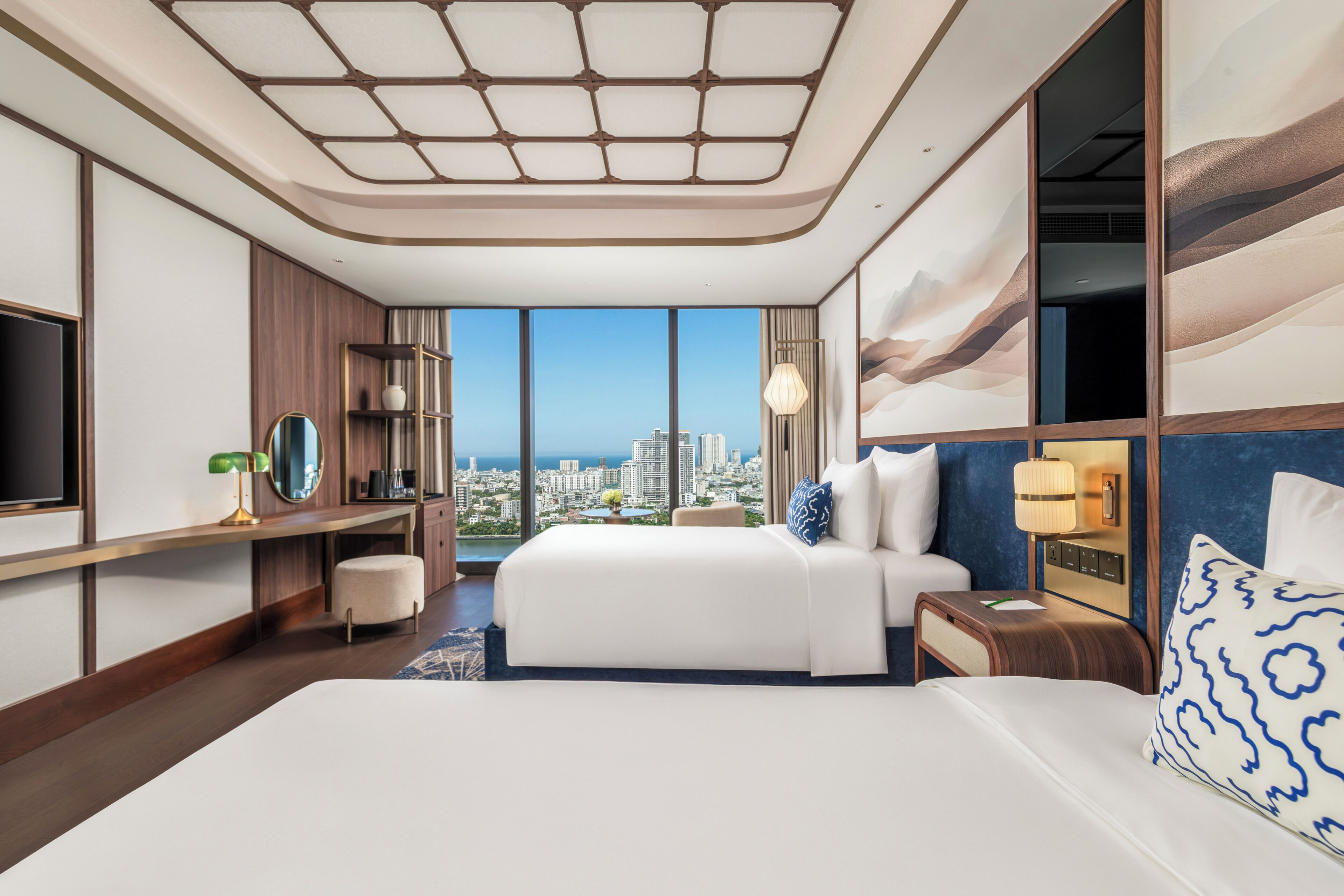 Habitación de hotel con una cama grande, un escritorio, un televisor y vistas a la ciudad.