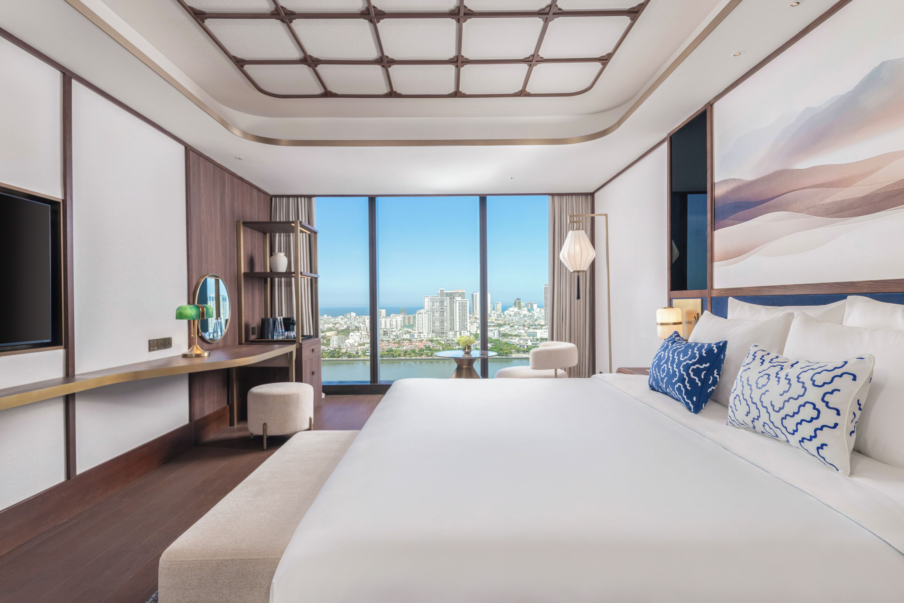 Habitación de hotel con una cama grande, un escritorio, una silla, un televisor y vistas a la ciudad.