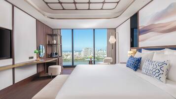 Habitación de hotel con una cama grande, un escritorio, una silla, un televisor y vistas a la ciudad.