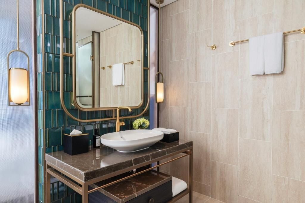 A modern bathroom with a large mirror, a vessel sink, and a marble countertop.